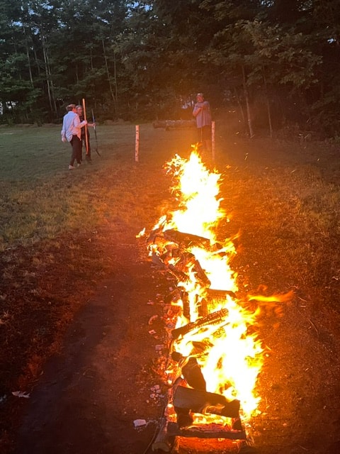 A long firewalk path blazing at night with participants standing at the edge